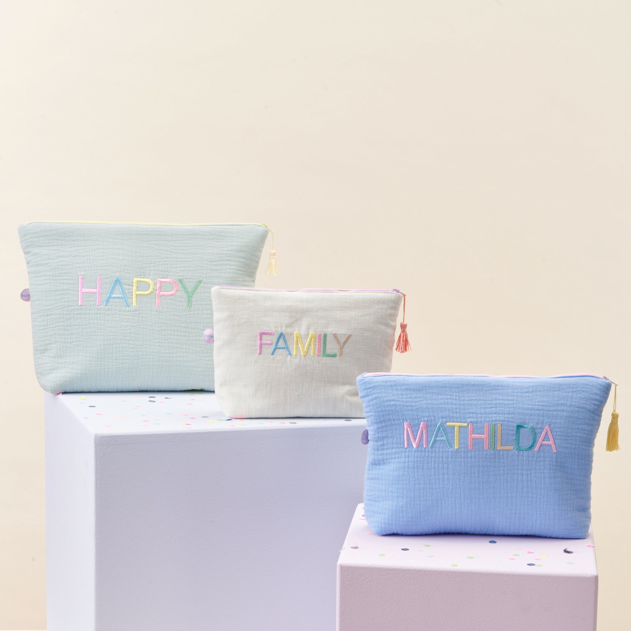 Drei personalisierte KULTURELLA Kulturtaschen aus Musselin mit bunter Stickerei der Wörter HAPPY, FAMILY und dem Namen MATHILDA – handgemacht in Hamburg, ideale Geschenkidee für Kinder und Familien